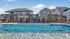 Elegant apartment complex featuring a large, inviting swimming pool with stylish wooden pergolas and comfortable lounge chairs for relaxation.