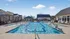 Inviting residential community pool surrounded by stylish lounge chairs and modern cabanas under a clear blue sky.