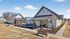 Charming community clubhouse with modern farmhouse design, beautifully landscaped gardens, and inviting pathways under a clear blue sky.