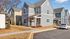 Charming, modern townhome with elegant gray and beige siding, set in a quiet, sunlit neighborhood featuring landscaped lawns and convenient parking.