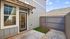 Charming enclosed patio with modern siding, glass door entrance, and quaint garden space, ideal for relaxation and entertaining.