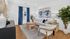 Chic living room with modern decor featuring a cozy white sofa, elegant wood furniture, vibrant blue curtains, and lush greenery.