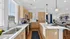 Bright, modern open-plan kitchen with sleek wood cabinets, stainless steel appliances, and a large dining island seamlessly flowing into a cozy living area.