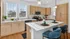Bright and modern kitchen with sleek wooden cabinets, white countertops, stylish breakfast bar, and vibrant blue chairs, perfect for a contemporary lifestyle.