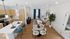 Bright and modern open-concept living space featuring a sleek kitchen with wooden cabinetry, a cozy dining area with a marble round table, and a stylish living room with vibrant decor and plant accents.