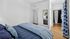 Inviting bedroom with a cozy blue-themed decor, featuring a plush bed, elegant hardwood flooring, and a modern en-suite bathroom.