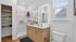 Elegant bathroom featuring a modern double vanity, large illuminated mirror, and chic glass shower, enhanced by natural light and warm wood flooring.