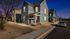 Charming modern two-story townhouse with inviting front porch, nestled in a serene and well-maintained neighborhood at dusk.