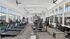 Bright, modern gym with state-of-the-art equipment including treadmills, weight machines, and exercise bikes, set against large windows offering a refreshing view.