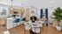 Modern open-plan living area with sleek kitchen, stylish blue bar stools, and elegant dining table, enhanced by abundant natural light.