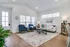 Inviting living room featuring elegant hardwood floors, chic blue armchairs, a cozy beige sofa, and abundant natural light through large windows, creating a warm and welcoming atmosphere.