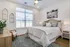 Bright and inviting bedroom with elegant decor, featuring a cozy bed, stylish artwork, and natural light streaming through large windows.