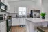 Sleek modern kitchen with stainless steel appliances, pristine white cabinets, and a cozy breakfast bar adorned with a vibrant green plant.
