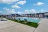 Elegant outdoor pool area featuring stylish lounge chairs, a pergola, and picturesque community backdrop under a vibrant blue sky.