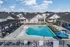 Luxurious community pool with elegant lounge chairs, surrounded by charming residential homes and blue skies.