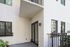 Charming apartment exterior with a private patio, sleek glass doors, and lush greenery, showcasing modern design and outdoor space.