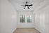 Bright and airy room featuring elegant wood flooring, white walls, and two large windows with leafy outdoor views, accented by a modern ceiling fan.