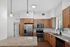 Modern kitchen with sleek stainless steel appliances, wooden cabinets, and elegant granite countertops, enhanced by stylish pendant lighting.