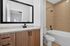 Modern bathroom featuring elegant wood cabinetry, a sleek granite countertop, and a spacious shower-tub combo with warm beige tiles.