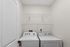 Modern laundry room featuring a sleek washer and dryer set beneath practical shelving for optimized storage.