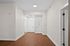 Inviting apartment hallway with elegant wood flooring and pristine white doors, offering a glimpse of contemporary living.