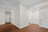 Inviting apartment entryway with warm hardwood floors, bright white walls, and multiple doors leading to spacious rooms.