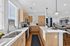 Bright and modern open-concept kitchen featuring sleek wooden cabinets, stainless steel appliances, and an inviting island overlooking a stylish living area.