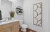Chic and modern bathroom featuring elegant wood cabinetry, sleek countertop sink, stylish wall shelving, and artistic decor.