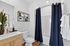 Modern bathroom featuring sleek wooden cabinetry, a large mirror, stylish shelving with decor, and elegant navy shower curtain.