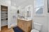 Elegant modern bathroom with sleek wooden vanity, illuminated mirror, and spacious glass shower, complete with stylish accessories and natural light.