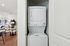 Chic apartment interior showcasing a stylish stackable washer and dryer unit seamlessly integrated next to a cozy living room with modern decor and elegant furnishings.
