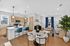 Bright and modern open-plan apartment with stylish kitchen island, luxurious dining area, and cozy living room accented by blue curtains and elegant decor.
