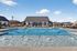 Inviting outdoor pool area with sun loungers and a modern clubhouse, perfect for relaxation and community gatherings.