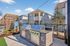 Charming outdoor grilling area with modern stainless steel barbecues and stylish wooden partitions, set against a backdrop of attractive townhouse architecture.
