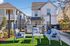 Charming outdoor seating area with stylish chairs and a table on vibrant green artificial turf, set against modern townhomes and equipped with a stainless steel grill perfect for entertaining.