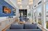 Elegant living space with cozy blue sofas, large windows offering abundant natural light, and a wall-mounted TV for entertainment.