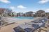 Luxurious apartment complex with sparkling outdoor pool, surrounded by modern loungers and elegant housing structures under a clear blue sky.