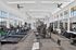 Spacious, sunlit gym with modern exercise equipment, featuring treadmills, ellipticals, and weight machines, offering a perfect fitness experience.