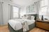 Bright and inviting bedroom featuring a plush green bed, stylish decor, and ample natural light, perfect for relaxation.