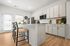 Modern kitchen with sleek cabinets, large island and bar seating, bathed in natural light through windows.