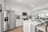 Modern open kitchen with sleek stainless-steel appliances, stylish white cabinetry, and elegant breakfast bar seating, seamlessly connected to a bright and lively living space.