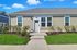 Charming single-story house with modern siding and lush green landscaping, set against a bright blue sky.