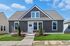 Charming single-story home with modern gray exterior, lush green lawn, and inviting entrance under a bright blue sky.
