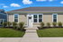 Charming single-story apartment with modern exterior, lush landscaping, and inviting entrance, perfect for comfortable living.