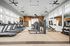 Modern fitness center with natural lighting, featuring treadmills, weight machines, and open space for workouts.