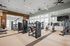 Spacious and modern gym with high-end fitness equipment, large windows for natural light, and a sleek interior design.