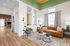 Elegant living room with high ceilings, a stylish green accent wall, and modern furnishings including a cozy leather sofa and contemporary decor.