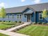 Charming single-story home with a striking blue facade, large windows, and lush landscaping.