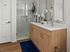 Elegant bathroom featuring a sleek double sink vanity with a modern wood finish, pristine glass shower enclosure, and stylish decor accents.