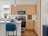 Elegant and modern kitchen with light wood cabinets, sleek appliances, and cozy breakfast bar seating in a sunlit space.